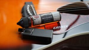 Vape device and Tarta de Queso nicotine salt e-liquid bottle resting on a Gretsch acoustic guitar body.