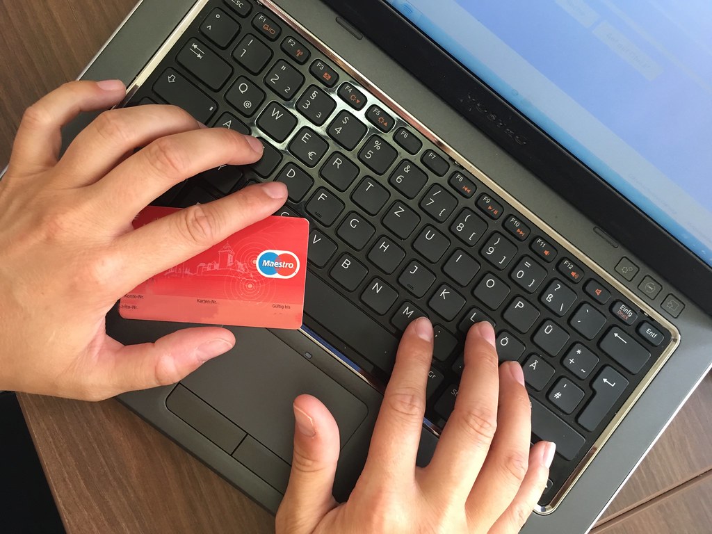 Hands typing on a laptop while holding a red credit card